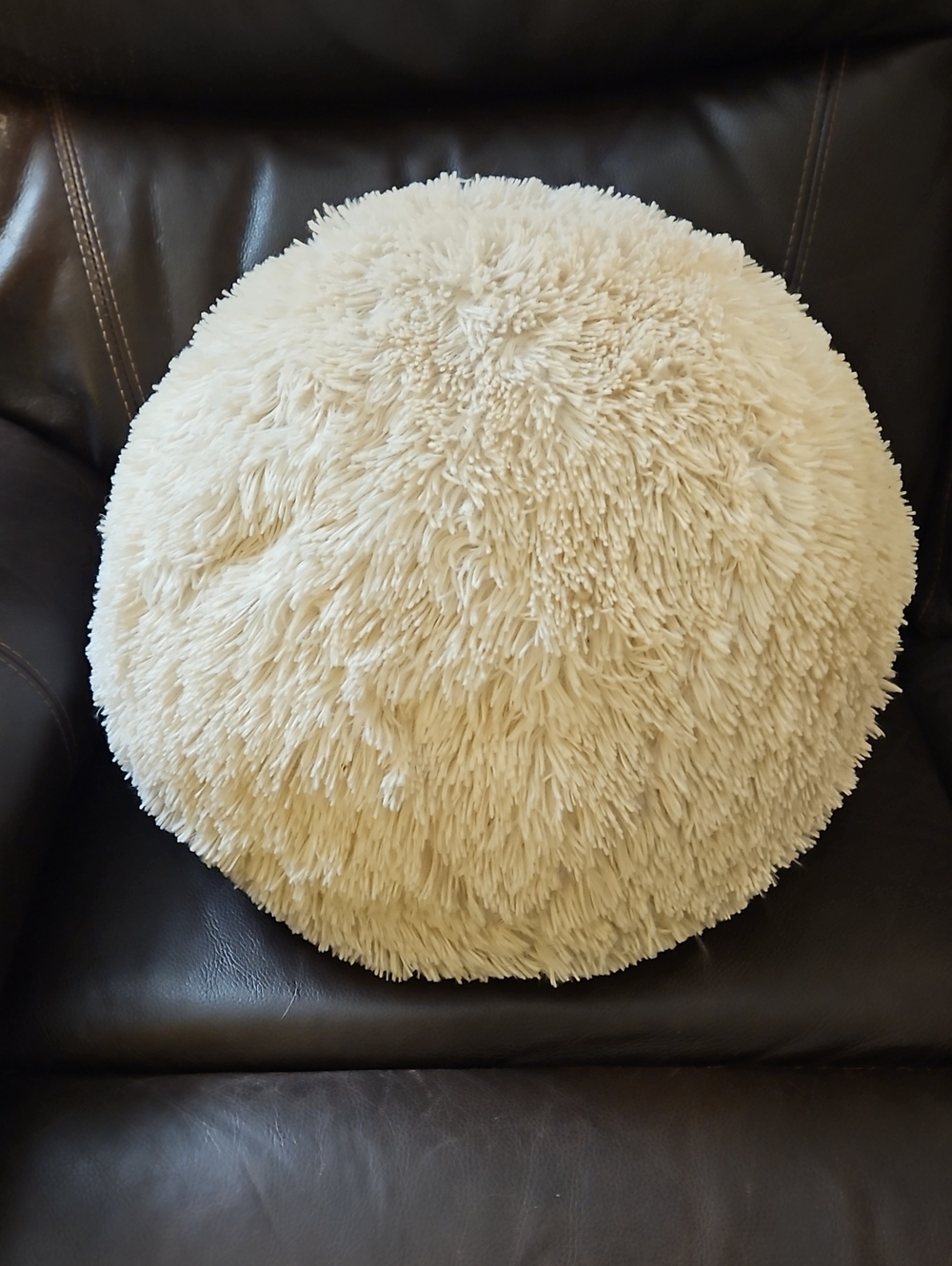 Fluffy, round cream-colored accent pillow w/ a textured shaggy finish